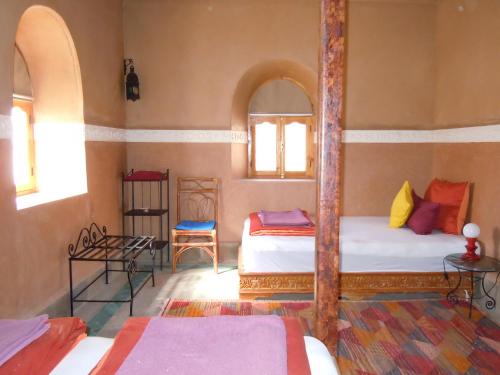 a bedroom with two beds and two windows at Kasbah Hotel Ait Omar in Nkob