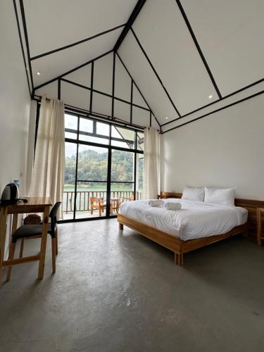a bedroom with a bed and a large window at The River Huts in Nongkhiaw