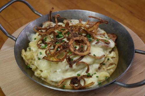 a metal bowl of food with onions on top at Gasthaus und Pension Halli-Galli in Passau