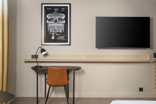 a table with a chair and a television on a wall at Hyatt Place Rouen in Rouen