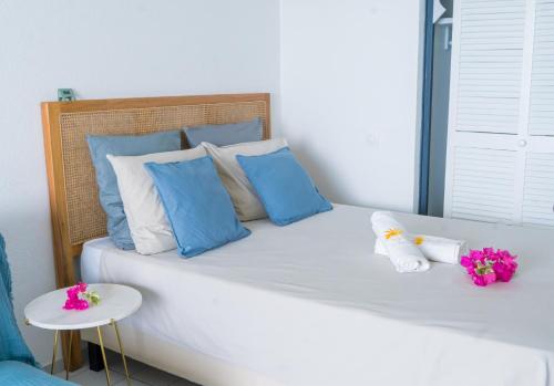 a bed with blue and white pillows and flowers on it at Gap Caraïbes in Le Diamant