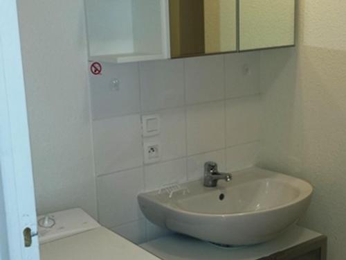 ein weißes Badezimmer mit Waschbecken und Spiegel in der Unterkunft Charmant studio au cœur de la station - FR-1-814-15 in Besse-et-Saint-Anastaise