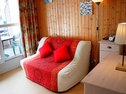 ein Wohnzimmer mit einem Sofa und roten Kissen in der Unterkunft Charmant studio au cœur de la station - FR-1-814-15 in Besse-et-Saint-Anastaise