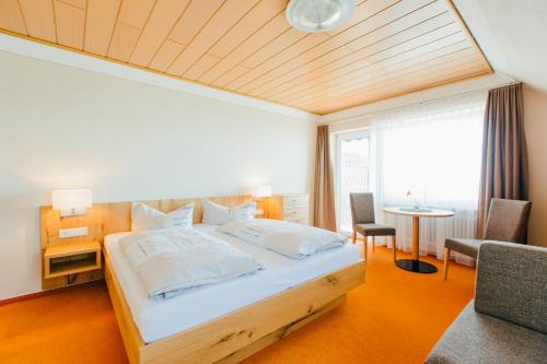 a bedroom with a bed and a table and a chair at Hotel Fischerhaus Garni in Meersburg