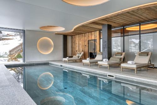 - une piscine dans une maison avec des chaises et des fenêtres dans l'établissement Chalet Ascension, à Combloux