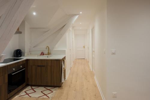 Il comprend une cuisine avec des murs blancs et du parquet. dans l'établissement Appartement Cosy, à Oloron-Sainte-Marie