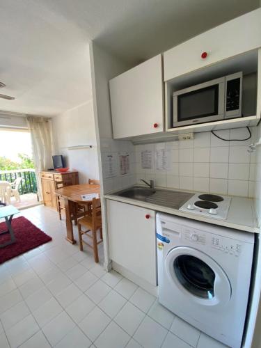 une cuisine avec un lave-linge et un micro-ondes dans l'établissement The echo of the waves, à Frontignan