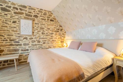 a bedroom with a bed and a brick wall at Le Penty - proche plages et centre in Concarneau