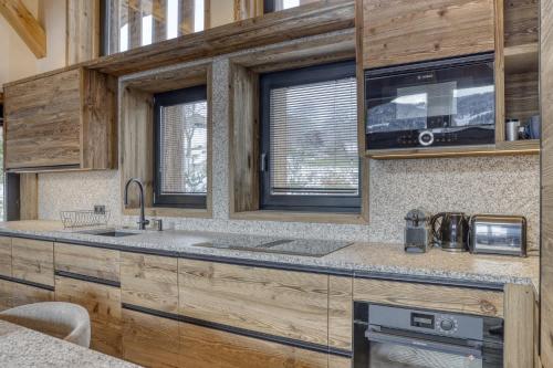 une cuisine avec des armoires en bois et un évier dans l'établissement Chalet Alpestre, à Combloux