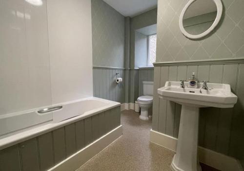 a bathroom with a sink and a tub and a toilet at Swiss Cottage in Ballindalloch