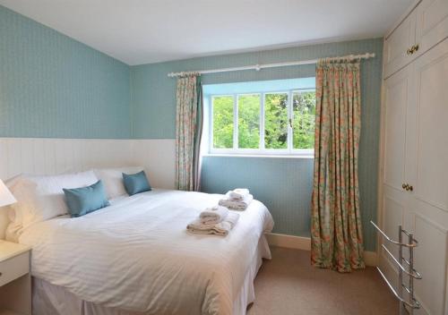 a bedroom with a large white bed with a window at Swiss Cottage in Ballindalloch