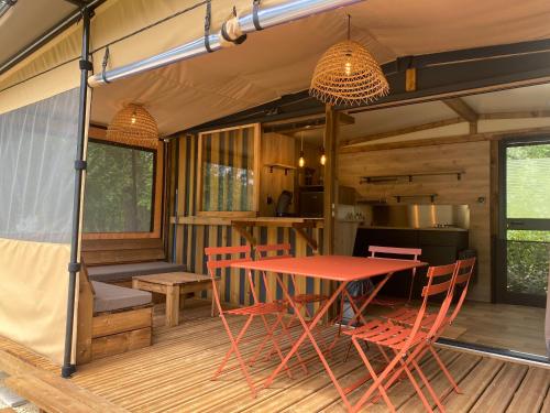 - une table et des chaises sur une terrasse couverte dans l'établissement Camping Le Marais Sauvage, à Le Mazeau