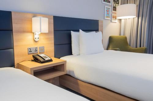 a hotel room with two beds and a phone on a table at Hilton Garden Inn Abingdon Oxford in Abingdon