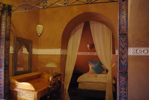 a room with a bedroom with a bed and a mirror at Kasbah Hotel Ait Omar in Nkob