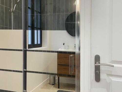 a bathroom with a sink and a mirror at La Maison Aux Fleurs by La Boîte En Plus in Courteuil