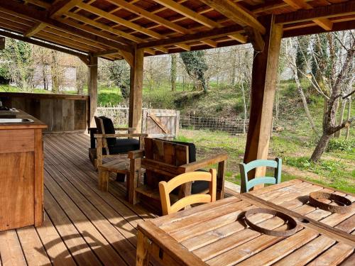 une terrasse en bois avec une table et des chaises en bois dans l'établissement Studio pour 2 - jardin clôturé - grande terrasse couverte, à Capdrot