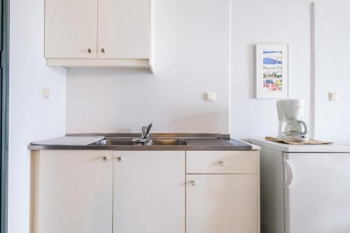 a kitchen with white cabinets and a sink at Casa del Sol in Kouniádhoi