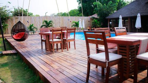 a wooden deck with tables and chairs next to a pool at Le Patio in Lomé