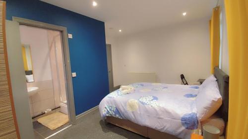 a bedroom with a bed and a blue wall at En-suite Double-Bedroom in the Heart of Eccles Manchester BH5 Perfect for Short Stays in Manchester