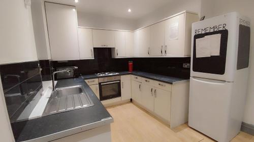 a kitchen with white cabinets and a white refrigerator at En-suite Double-Bedroom in the Heart of Eccles Manchester BH5 Perfect for Short Stays in Manchester
