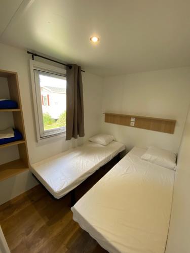 2 łóżka w małym pokoju z oknem w obiekcie Camping de l'Arnel w mieście Villeneuve-lès-Maguelone