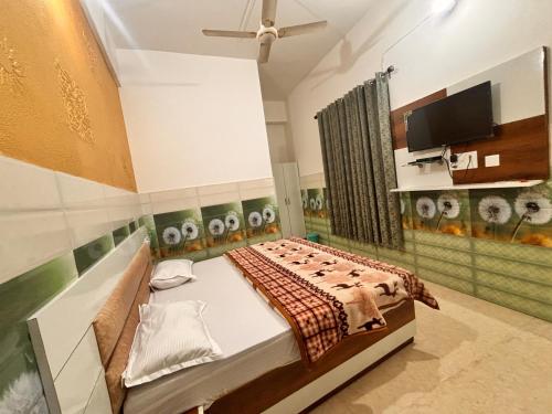 a bedroom with a bed and a tv in it at Lotus Homestay in Bharwain