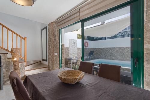 Un comedor con mesa y una piscina. en Sweet Home Playa Blanca, en Playa Blanca