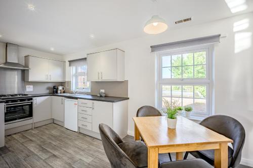 a kitchen with white cabinets and a table and chairs at Cosy Apartment in Wetheral,Cumbria in Wetheral