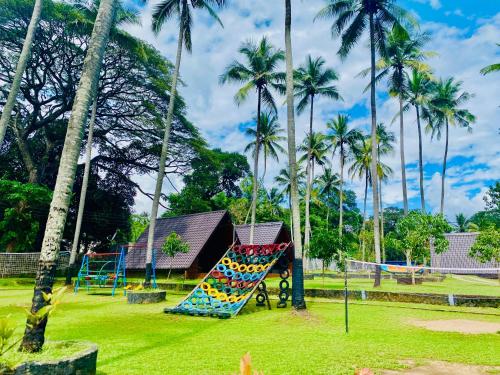 a playground with a colorful slide in a park with palm trees at Deduru Cabana Nature Resort in Kurunegala