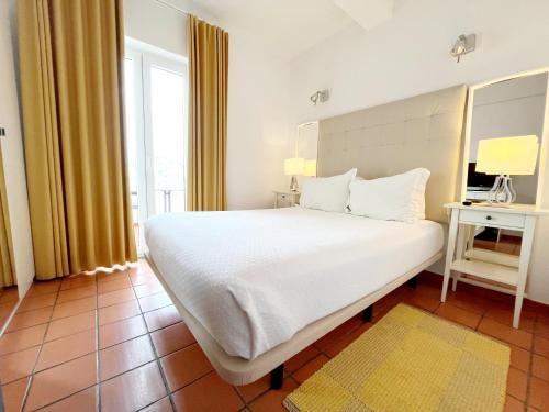 a bedroom with a large white bed and a window at Apartamentos da Vila - Duna Parque Resorts & Hotels in Vila Nova de Milfontes