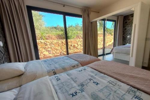 a bedroom with a bed and a large window at Casa-Cidreira-Villa-4P-en-baby-with-private-pool-in-a-natural-setting in São Bartolomeu de Messines