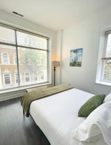 a bedroom with a large white bed and two windows at Yale Modern Downtown Chateau in New Haven