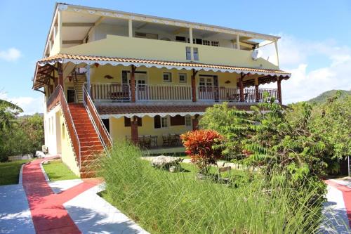 a large yellow house with a balcony on top of it at Domaine Macabou in Le Vauclin