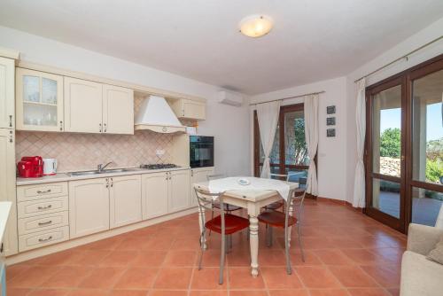 a kitchen with white cabinets and a table and chairs at Villa Alice in Li Valcaggi