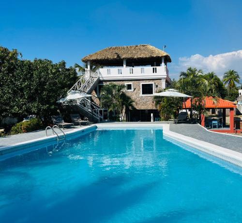 a swimming pool in front of a house with a thatch roof at Villa Rosa Bella Perfect for families or groups in Palmar de Ocoa