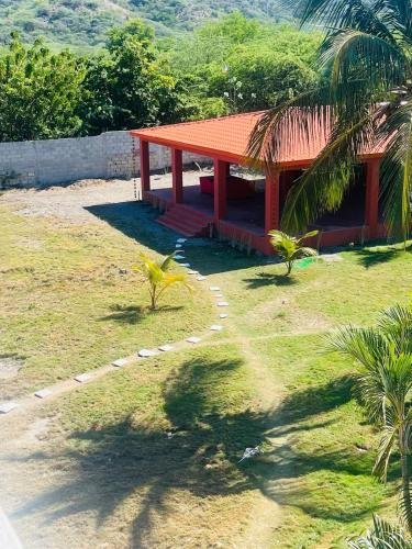 a house with a red roof in the grass at Villa Rosa Bella Perfect for families or groups in Palmar de Ocoa