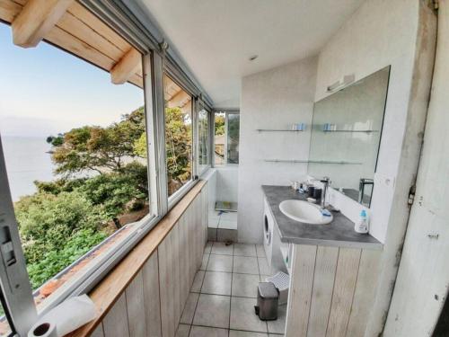La salle de bains est pourvue d'un lavabo et offre une vue sur l'océan. dans l'établissement Maison charmante avec vue sur la mer à Fouras, à Fouras