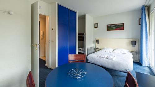 a hotel room with a bed and a blue table at Vacancéole - Appart'Vacances Pyrénées 2000 in Bolquere Pyrenees 2000