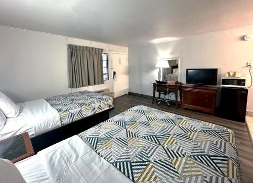 a hotel room with two beds and a flat screen tv at Red Carpet Inn - Stamford in Stamford