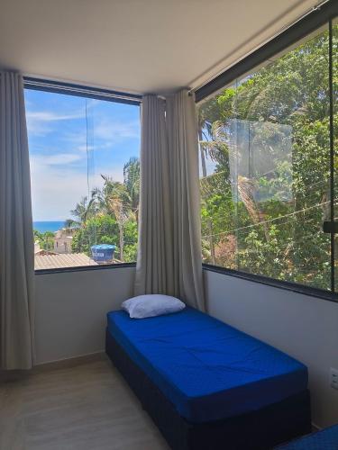 a bedroom with a blue bed and a large window at Temporada Peterle | Cobertura Irirí in Anchieta