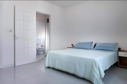 a white bedroom with a bed and a bathroom at Villa Leonardo con piscina privata in Tiggiano