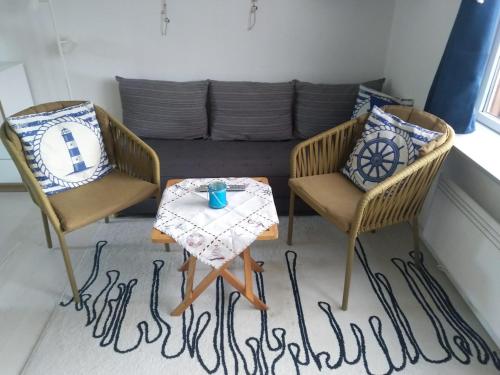 two chairs and a table in a room with a couch at Gemütliche Wohnung in Strandnähe in Neksø
