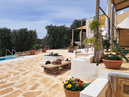 切列梅萨皮卡Conibianchi Trulli & YurtArt House的有鲜花、桌子和游泳池的露台