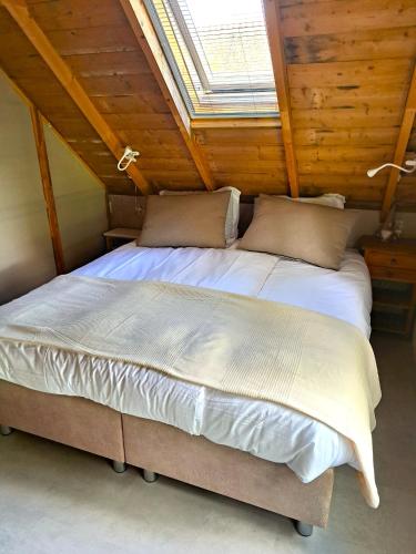 a bedroom with a large bed in a attic at Vakantiehuis Het Wonder in Siegerswoude