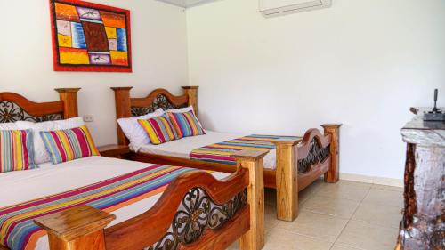 a bedroom with two beds and a picture on the wall at Finca Nuevo Monarca in Pereira