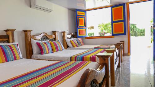 a room with three beds with colorful striped pillows at Finca Nuevo Monarca in Pereira