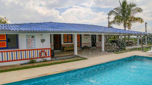 a house with a blue roof and a swimming pool at Finca Nuevo Monarca in Pereira