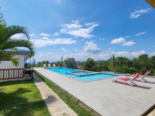a swimming pool in a yard with two chairs around it at Finca Nuevo Monarca in Pereira