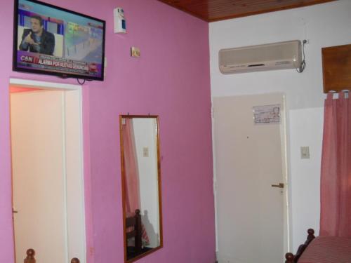 a room with a tv on the wall and a mirror at Dennisse Hotel in Victoria