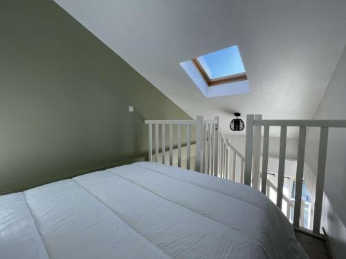 une chambre avec un lit blanc et une lucarne dans l'établissement Appt Studio mezza LA ROCHELLE - LR530-008, à La Rochelle
